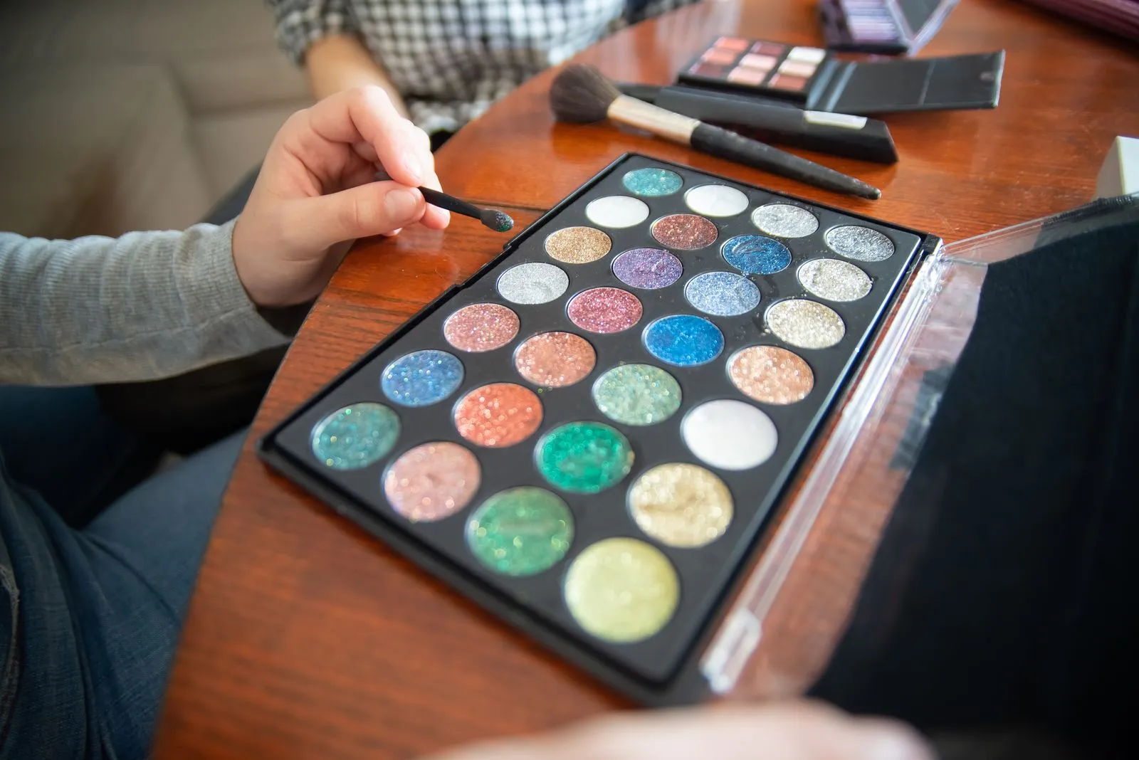 Vibrant glitter eyeshadows with makeup brushes on wooden table