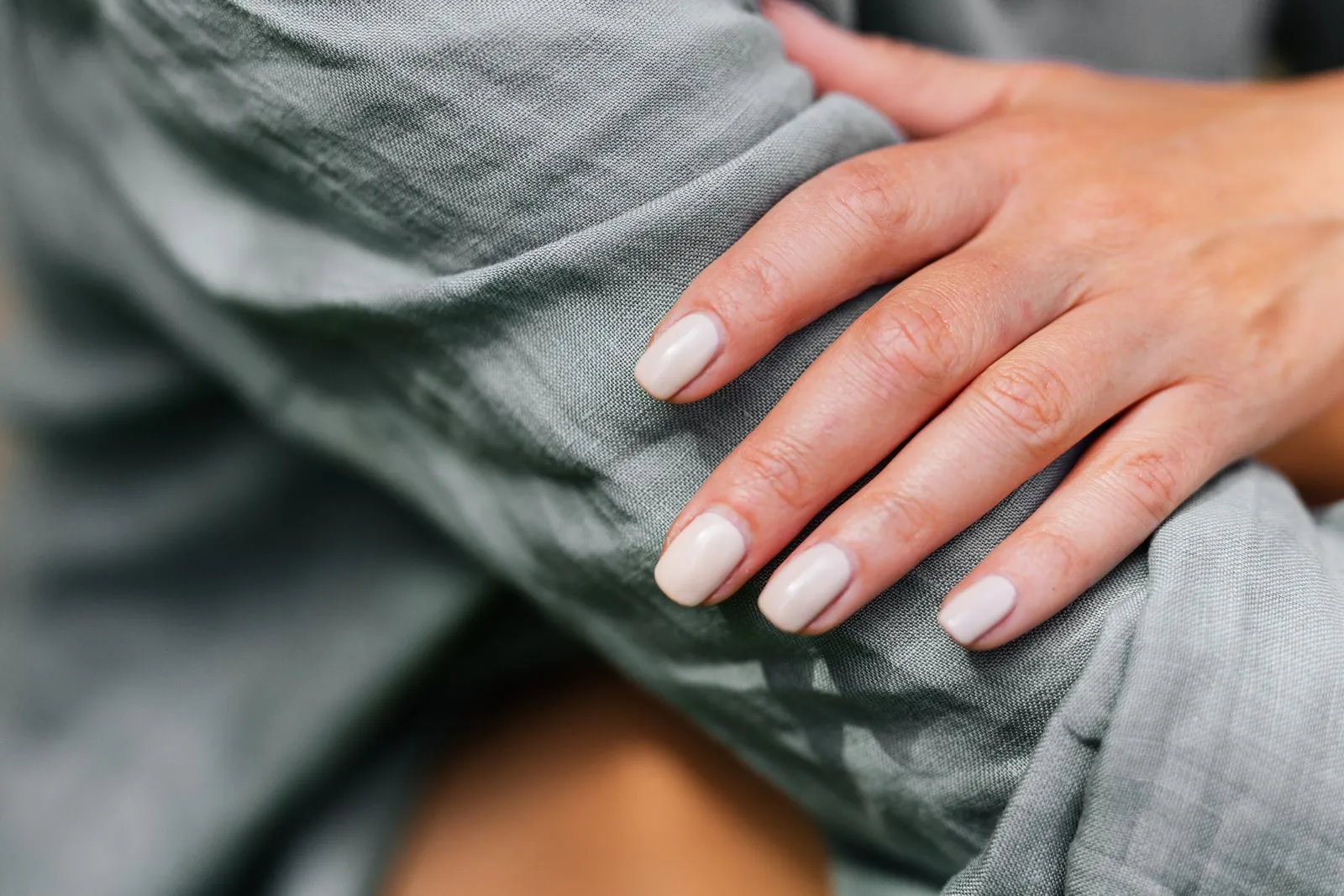 Close-up of a neatly manicured hand resting on a green sleeve