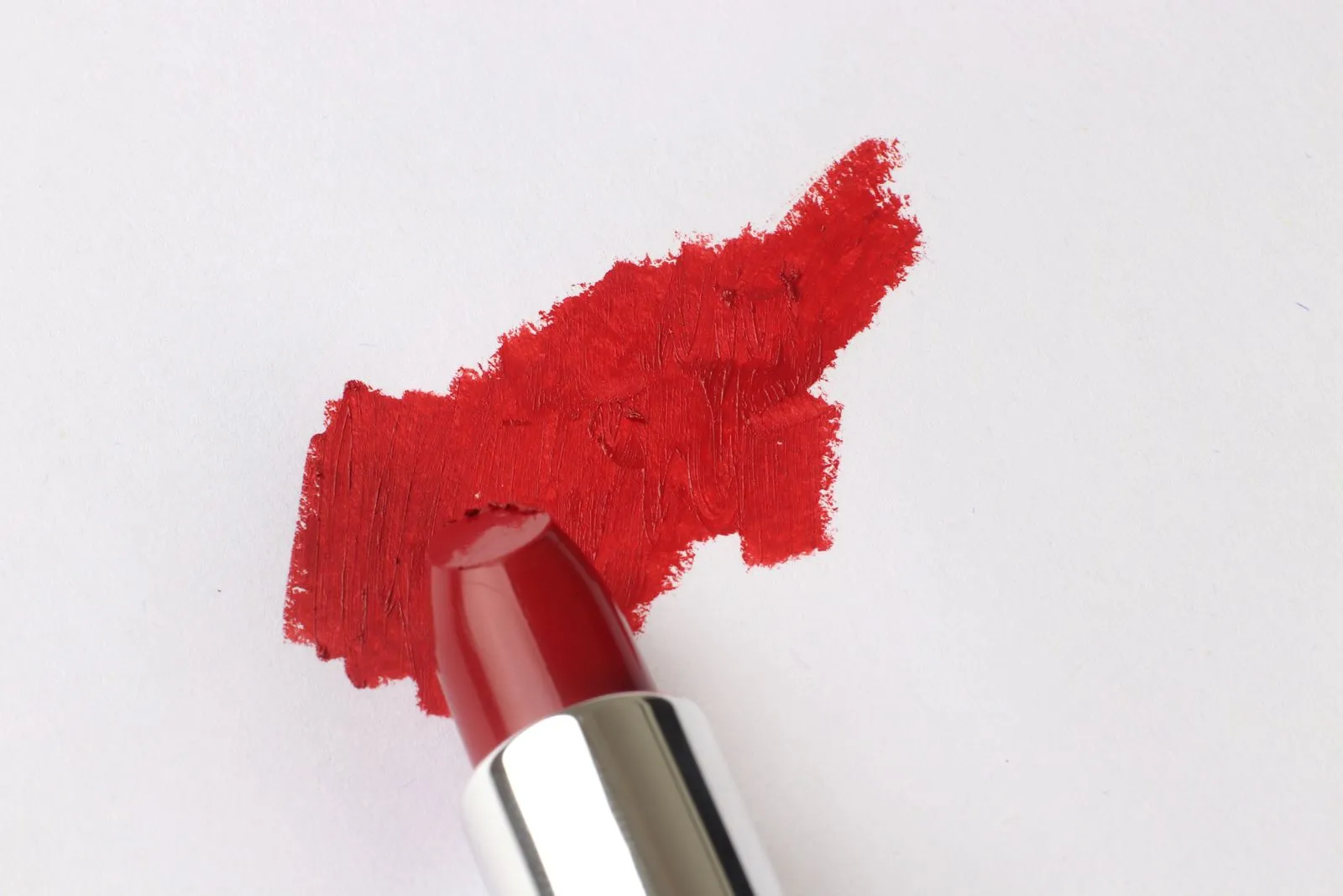 A vibrant red lipstick swatch on a white background emphasizing cosmetic texture.