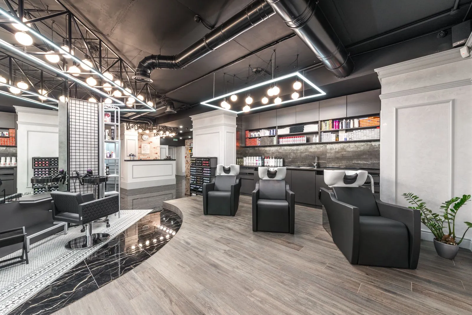 Comfortable backwash chairs with sinks near potted plant placed in contemporary beauty salon with bright illumination an