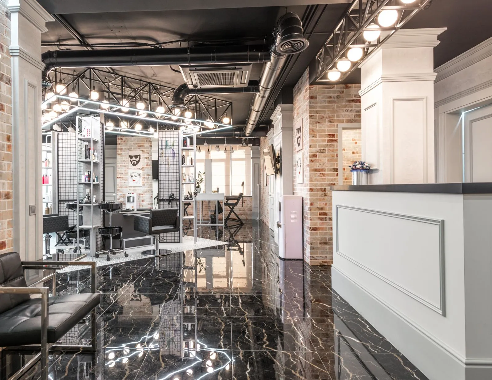 Reception counter placed in spacious stylish beauty salon with black chairs and decorated bricks walls with paintings un