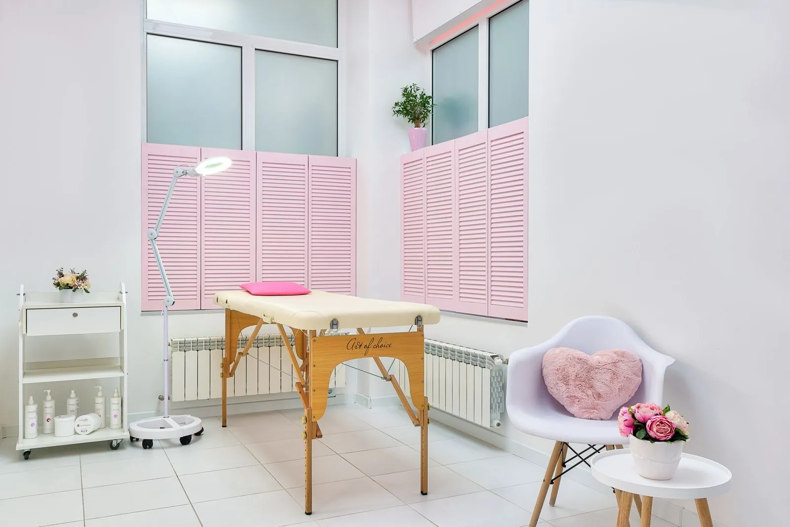 Interior of modern beauty salon decorated with blooming flowers with couch and bottles of skin care products on shelf