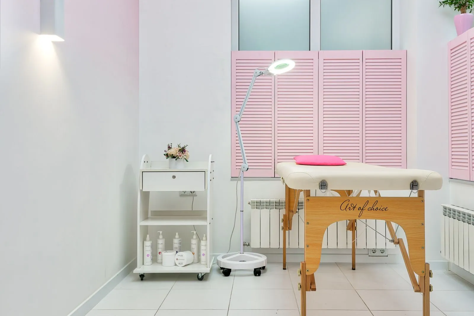 Interior of modern beauty salon with assorted skin products and couch for clients placed against window covered with shu