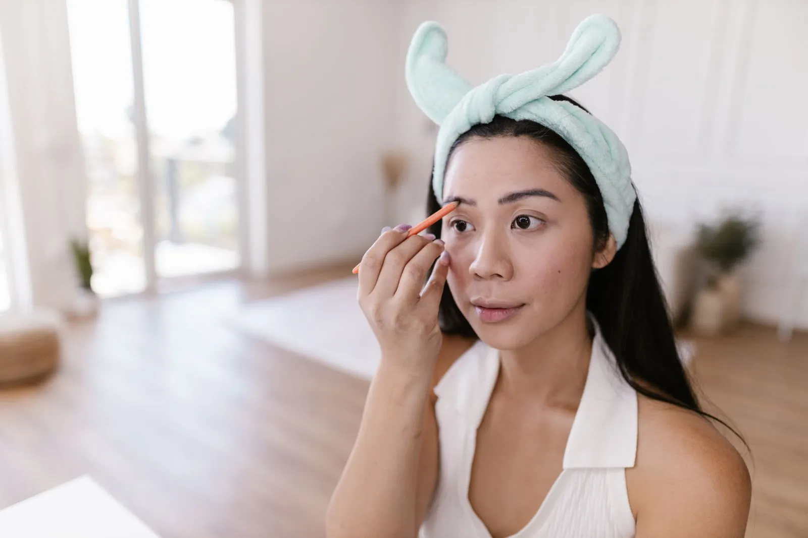 Woman using an eyebrow pencil indoors