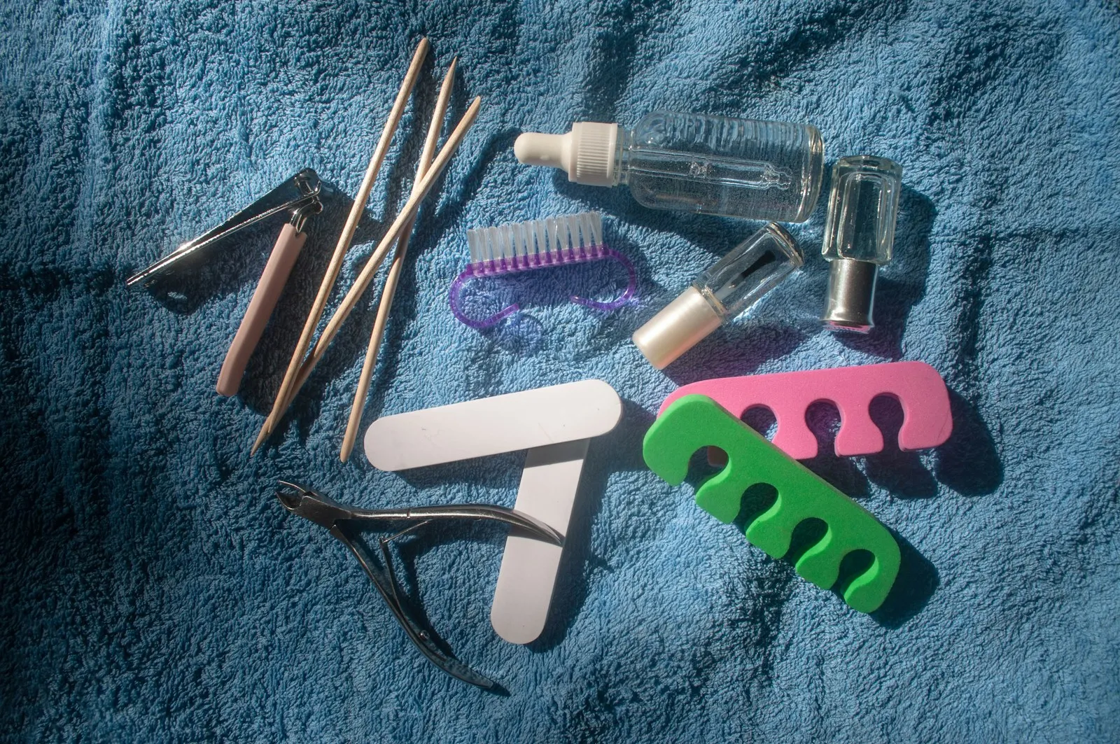 Top view set of pedicure/manicure equipment on a blue towel background on a sunny day. Pedicure kit. Transparent strengt