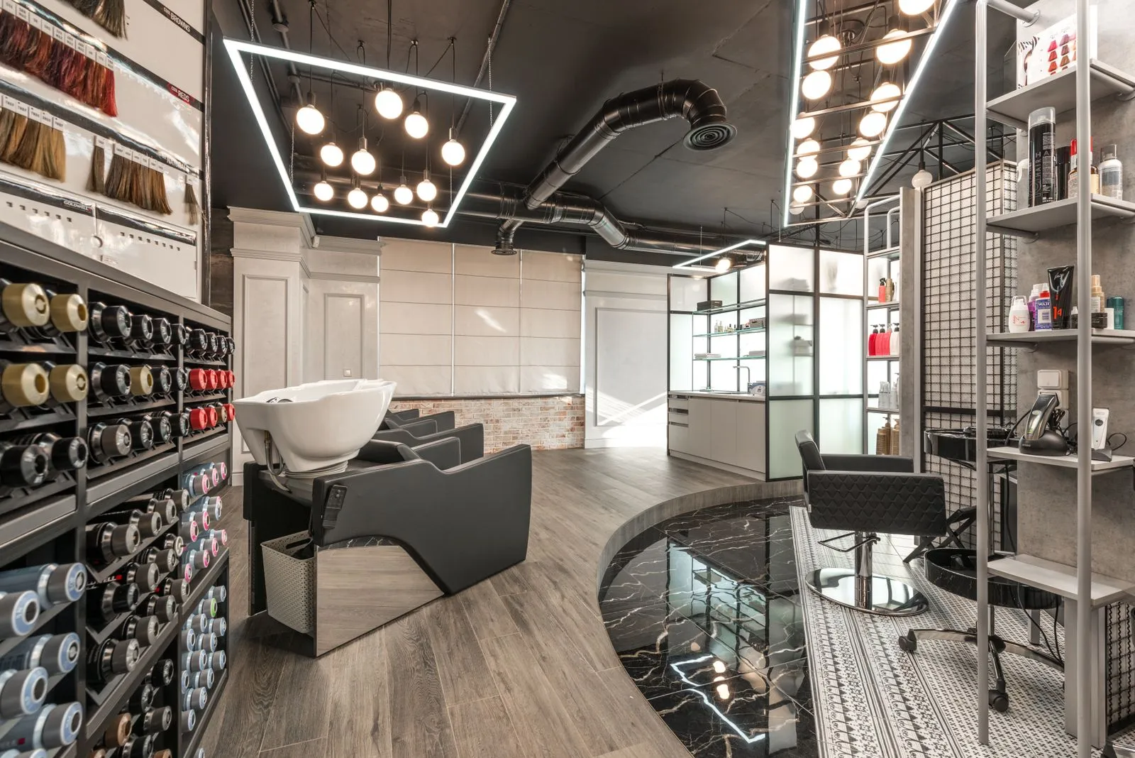 Black backwash chair with white sink placed in modern stylish beauty salon with various cosmetology products and bright