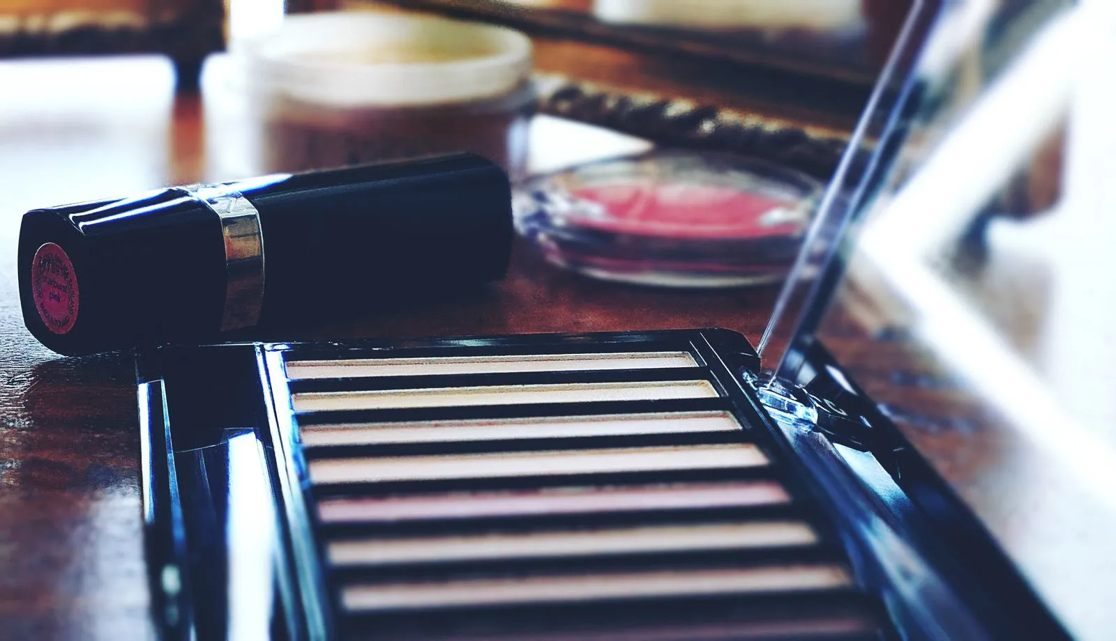 A collection of makeup products including lipstick and eyeshadow on a wooden table
