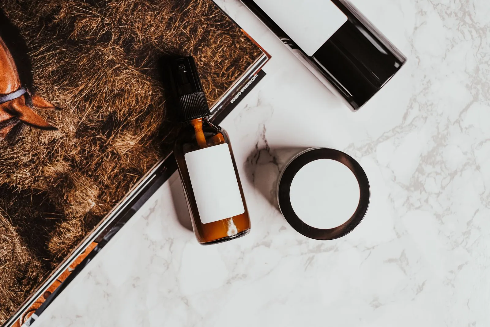 A stylish flatlay of skincare products with a magazine on a marble surface