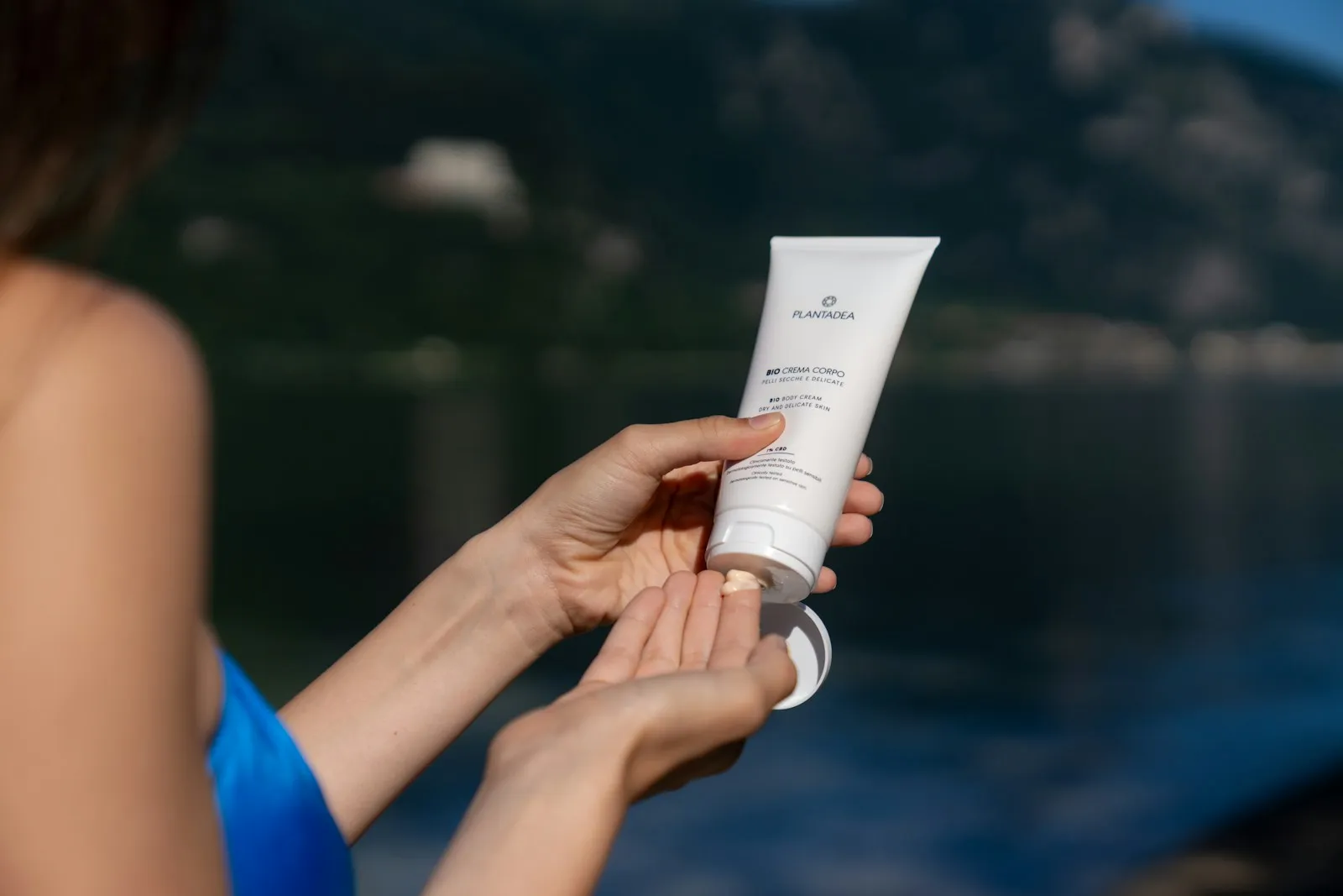 Woman applies lotion from a tube outdoors