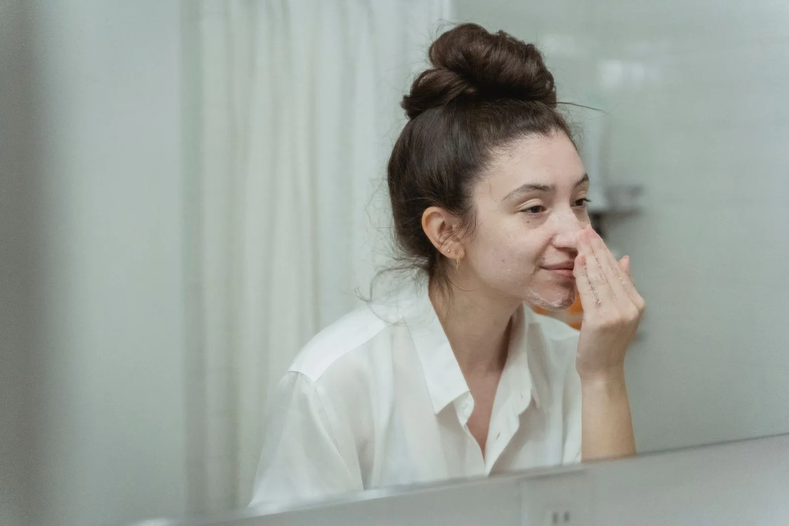 Woman applying face cream in bathroom