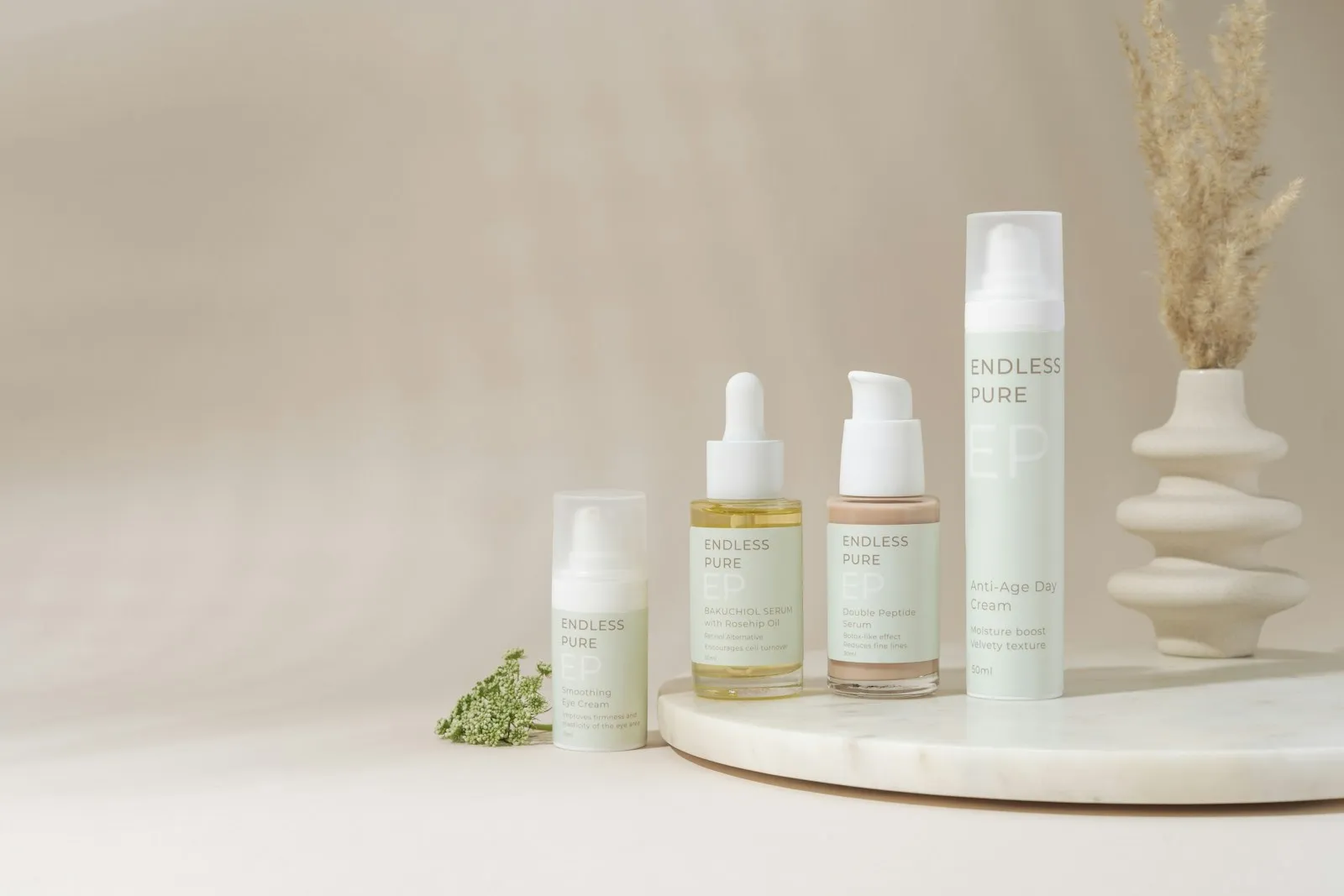 A beautifully arranged display of elegant skincare products on a marble tray against a soft, beige backdrop. The collect