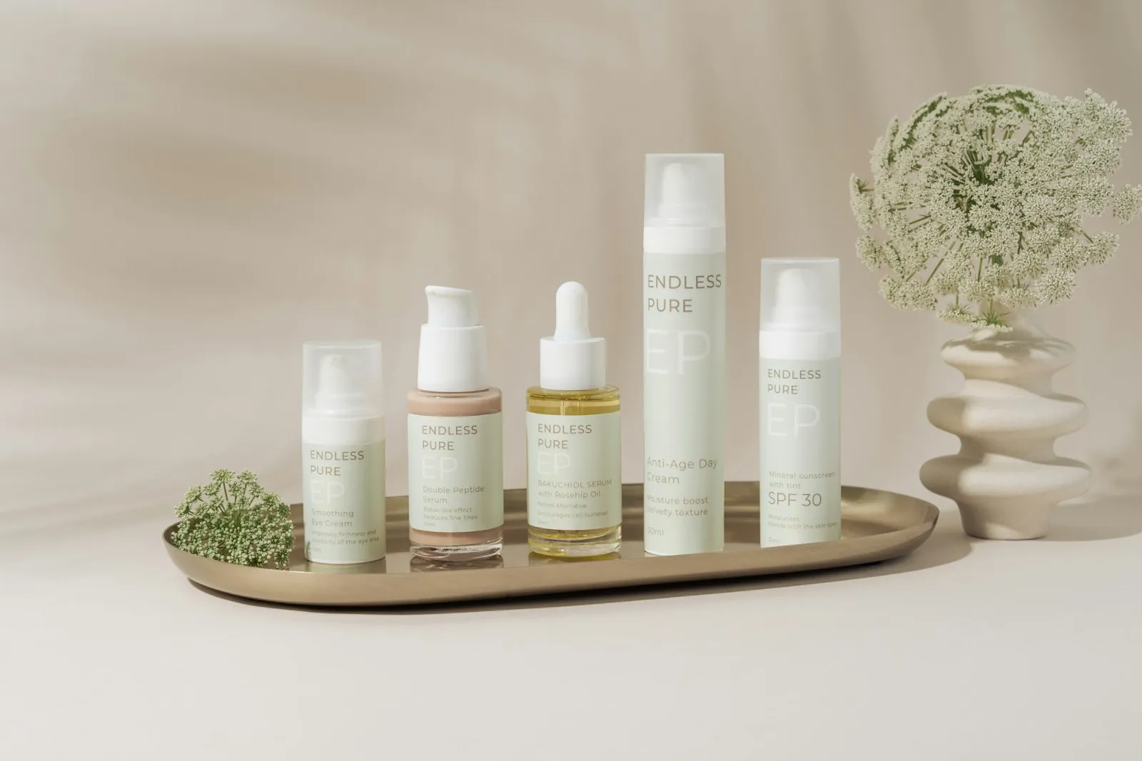 A beautifully arranged display of elegant skincare products on a marble tray against a soft, beige backdrop. The collect
