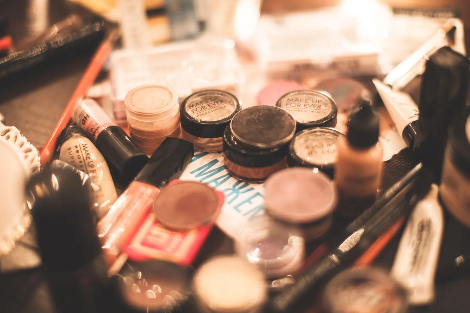 A vibrant collection of cosmetics including eyeshadows, lipsticks, and brushes on a table.