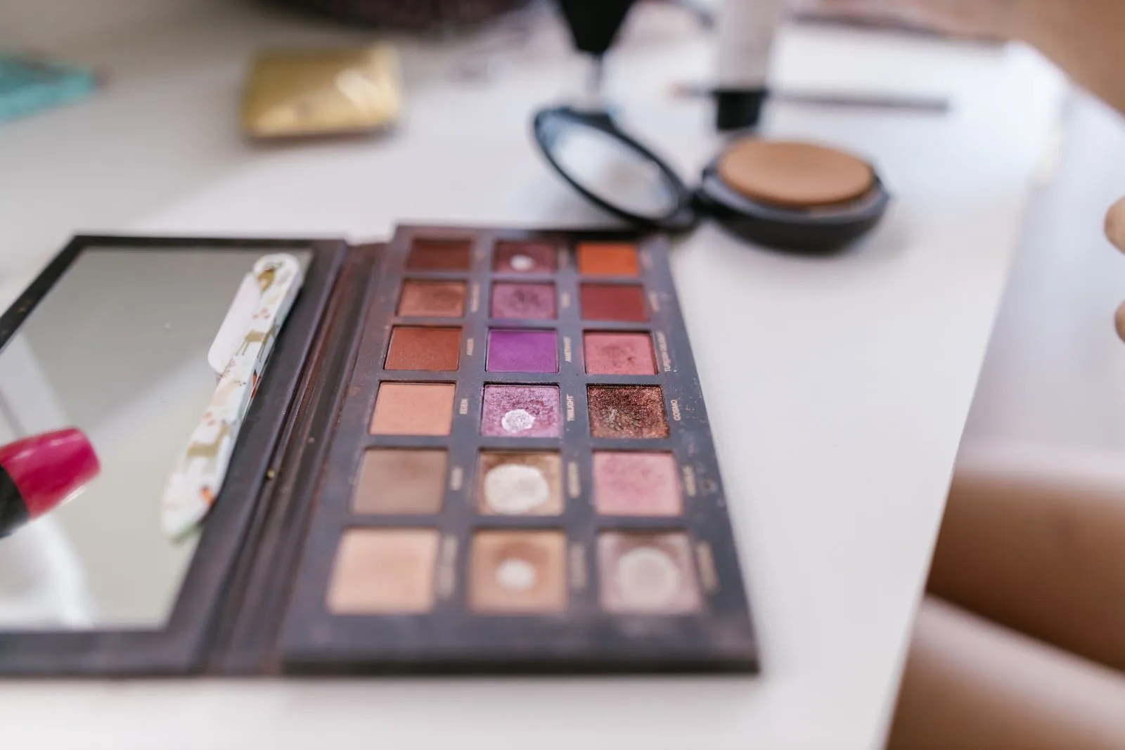 A detailed close-up of a well-used makeup palette on a white table