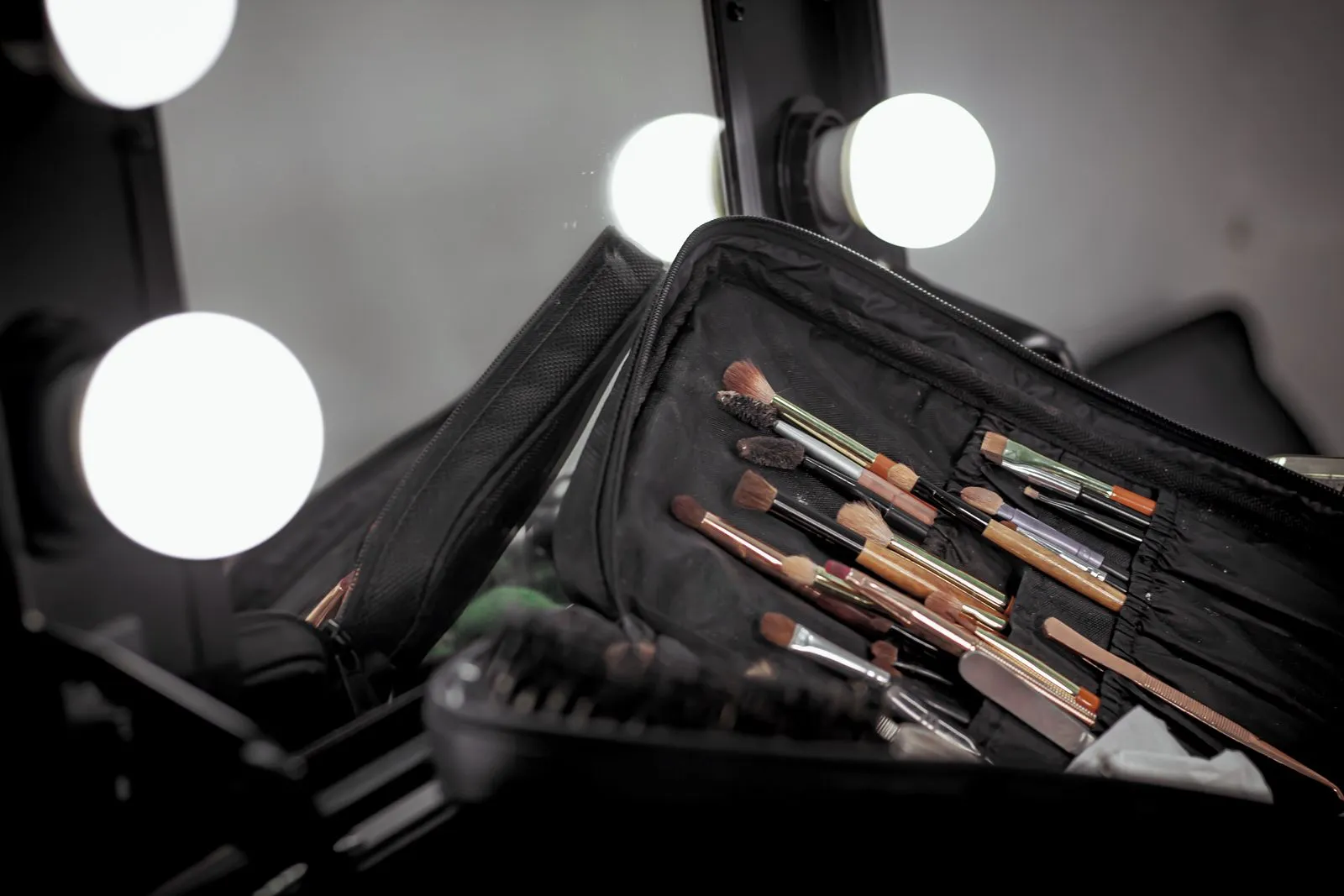 A set of makeup brushes on a vanity table with bright lights