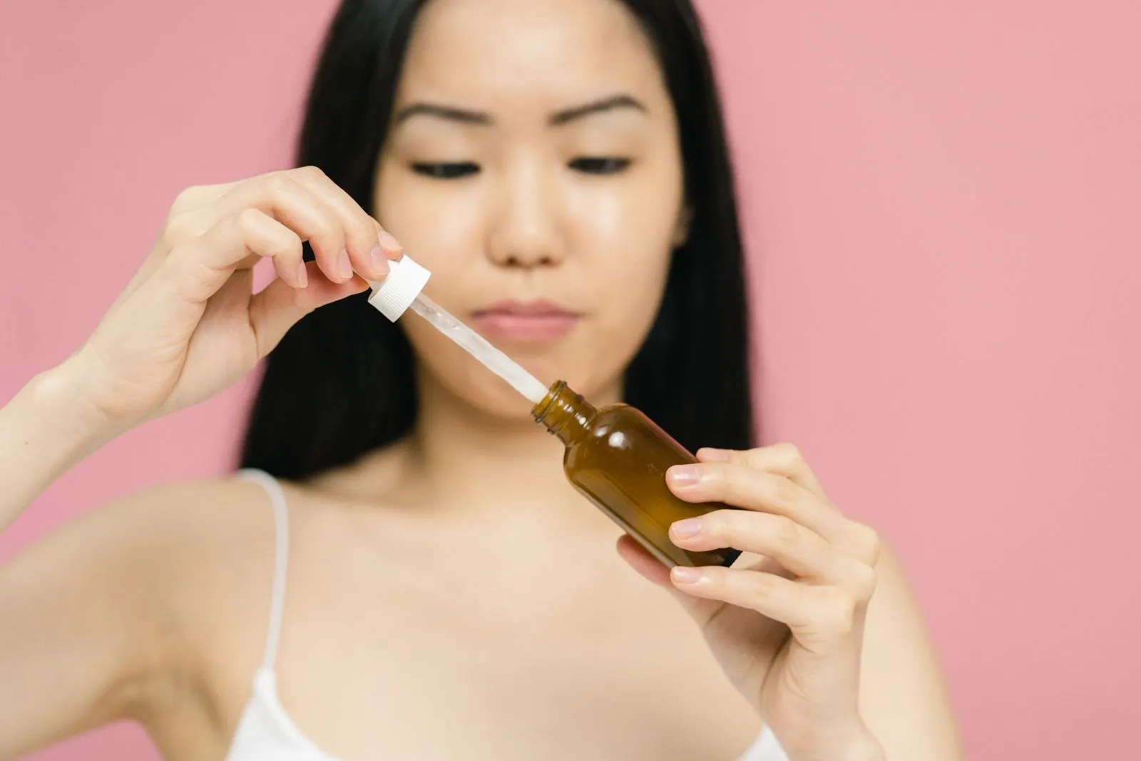 Close-up of a woman holding a serum bottle with a dropper