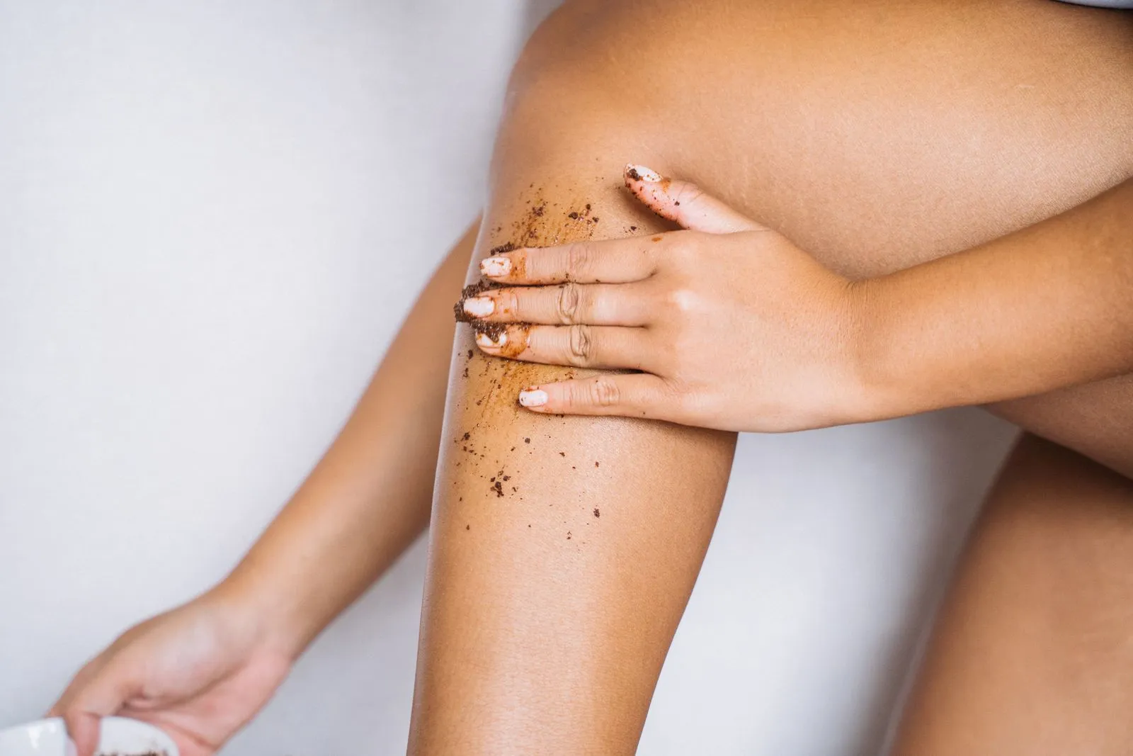 Woman applying exfoliating scrub to her leg for smooth skin care.