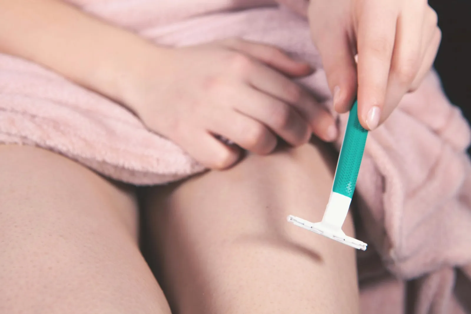 Close up of young girl shaving her leg in the bathroom.