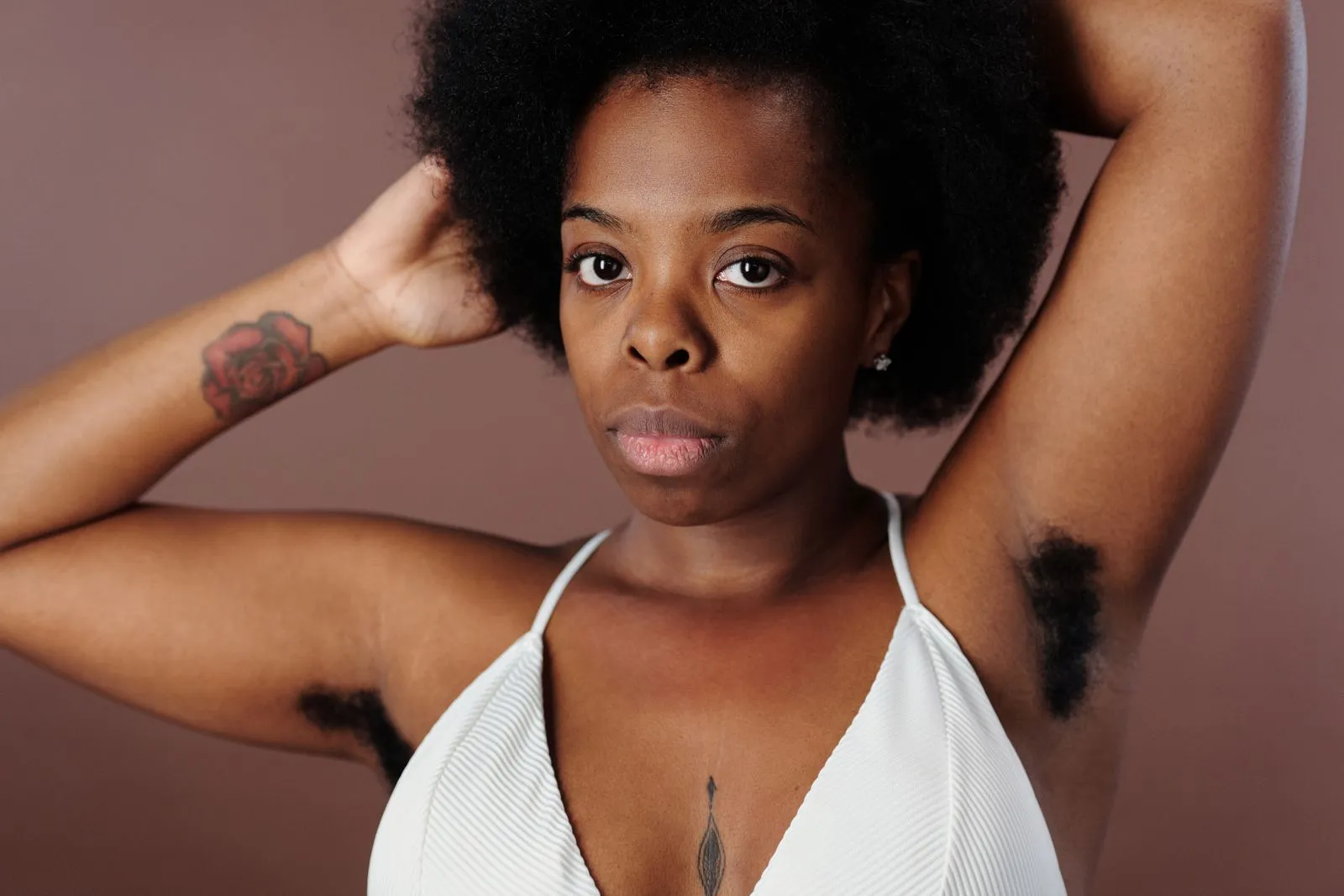 Close-up portrait of a confident woman with raised arms and natural beauty, embracing body positivity.