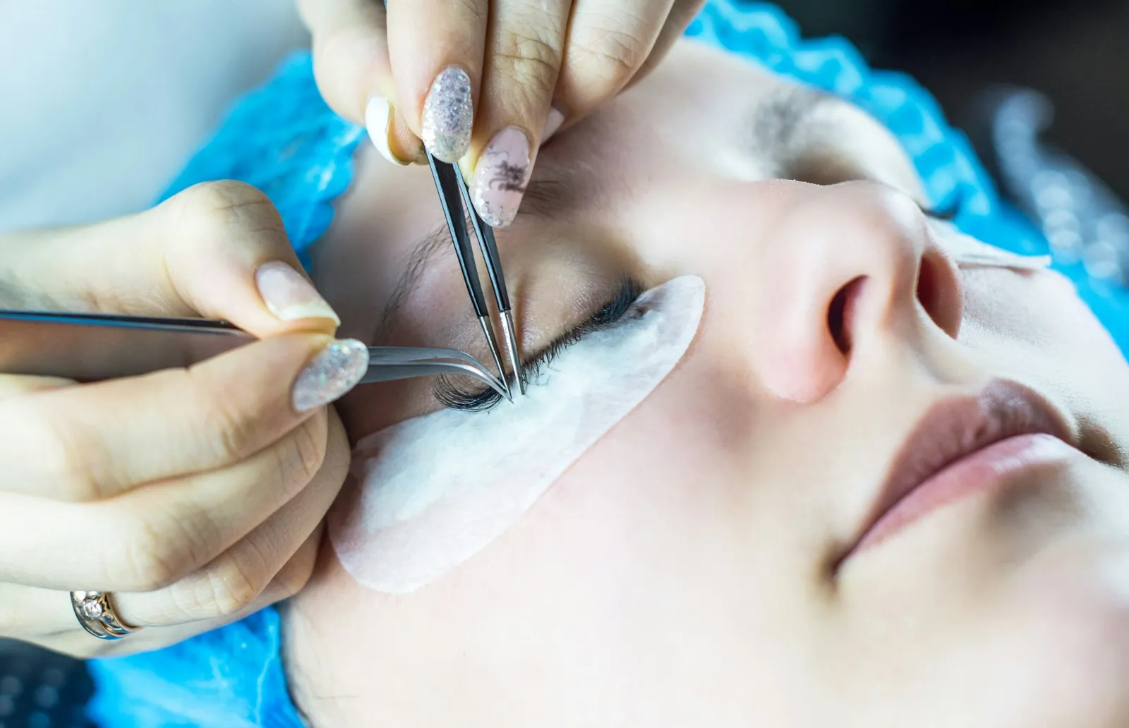 Young woman undergoing eyelash extensions procedure, closeup. More of my photos and videos Adobe Stock:http://bit.ly/3Rq