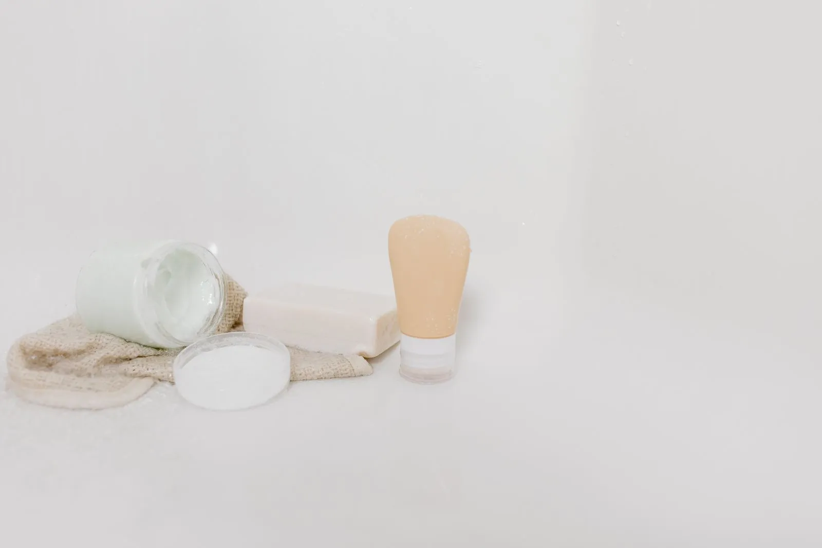 Minimalist setup of skincare products including cream, soap, and lotion on a white surface for beauty and self-care them