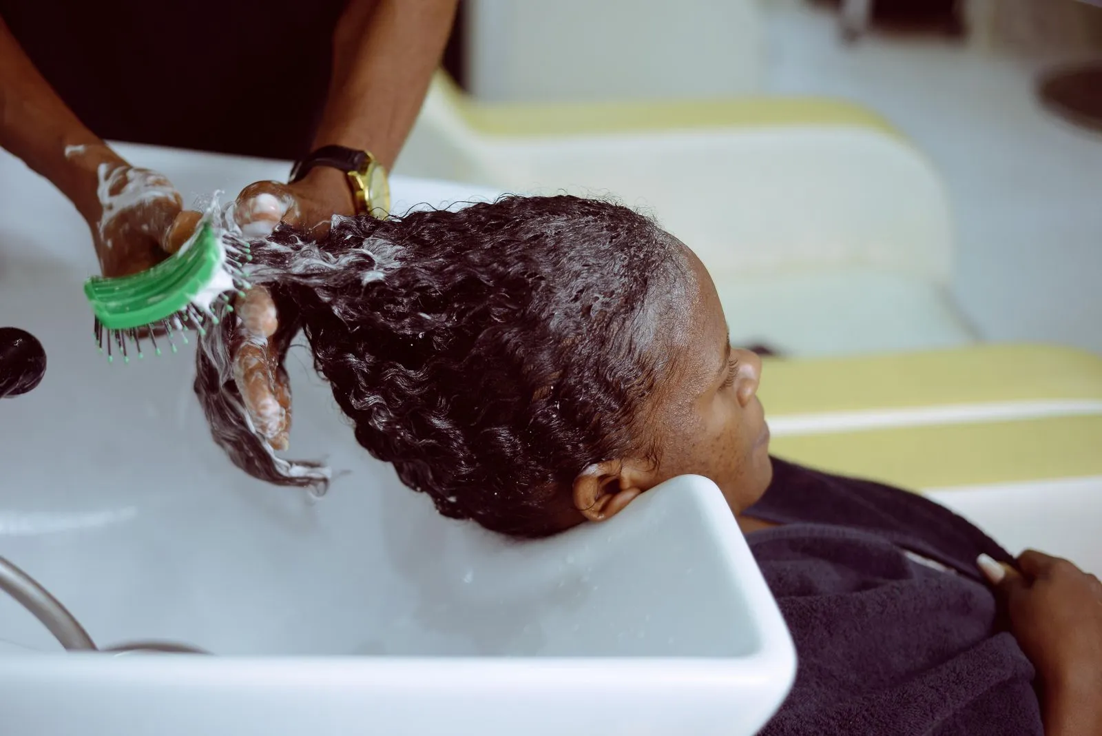 A woman receives a hair wash at a salon with foam and care.
