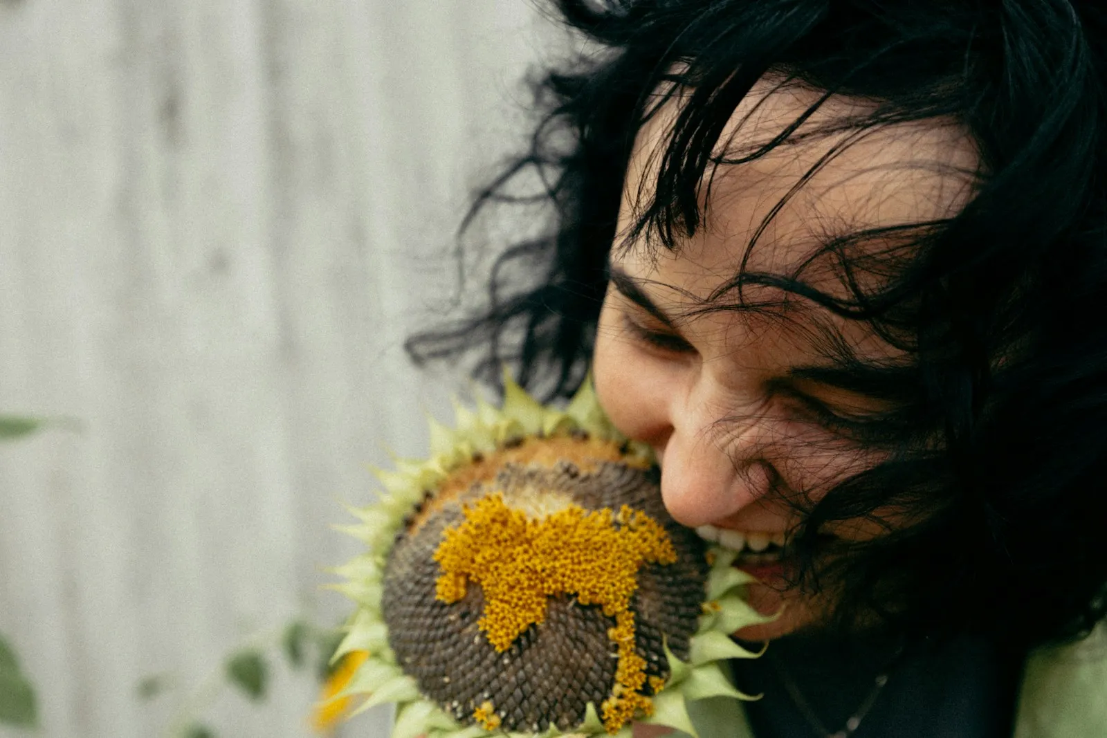 Woman with dark hair bites into a sunflower