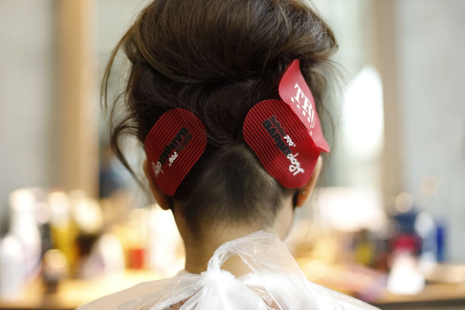 Back view of woman with brown hair and clips in salon setting.