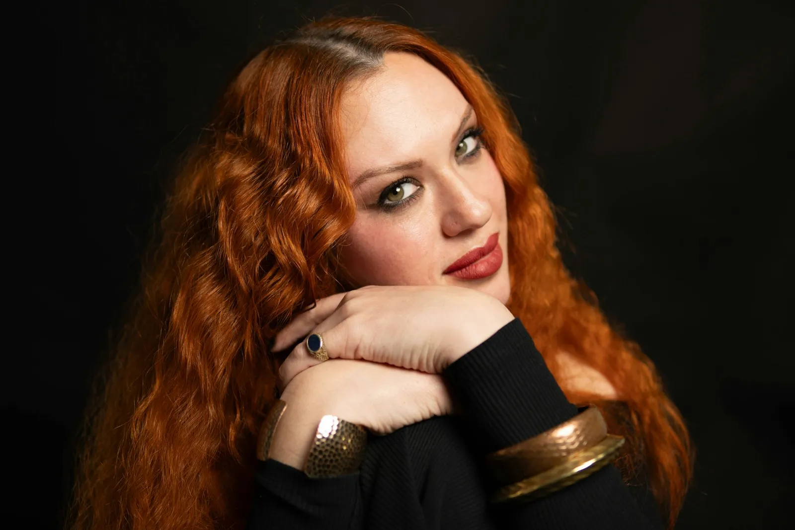 Portrait of a red-haired woman with natural freckles, looking confidently at the camera. Soft natural light highlights h