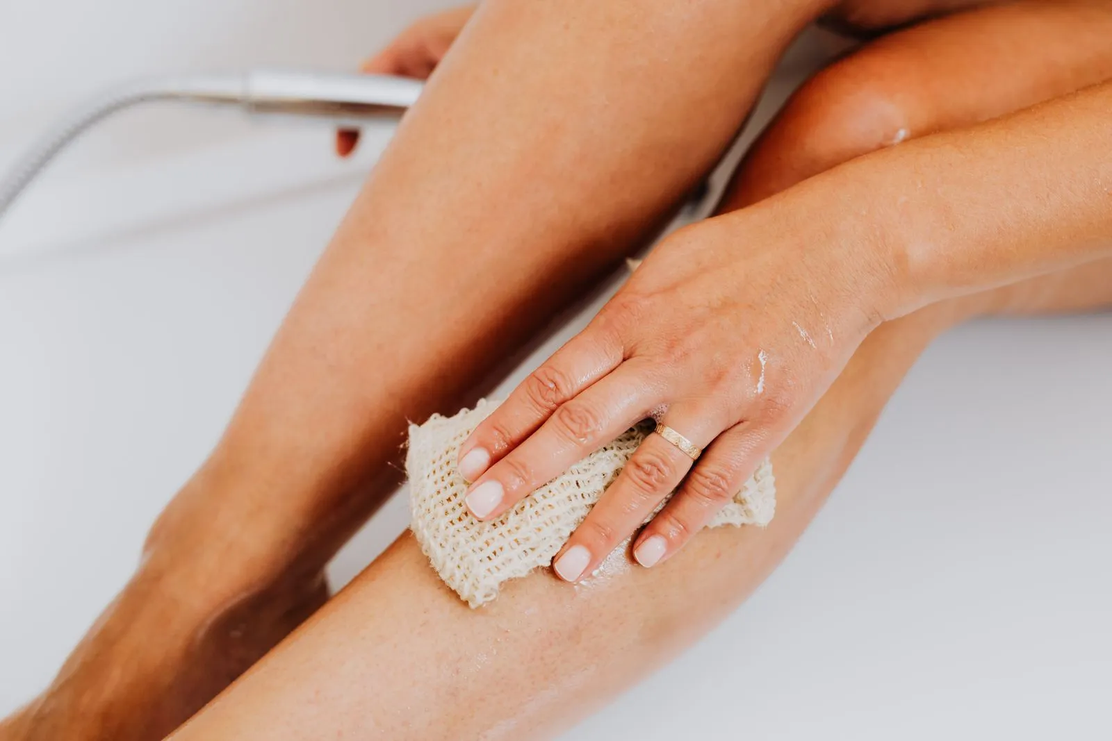 A close-up shot of a hand scrubbing a leg with a loofah