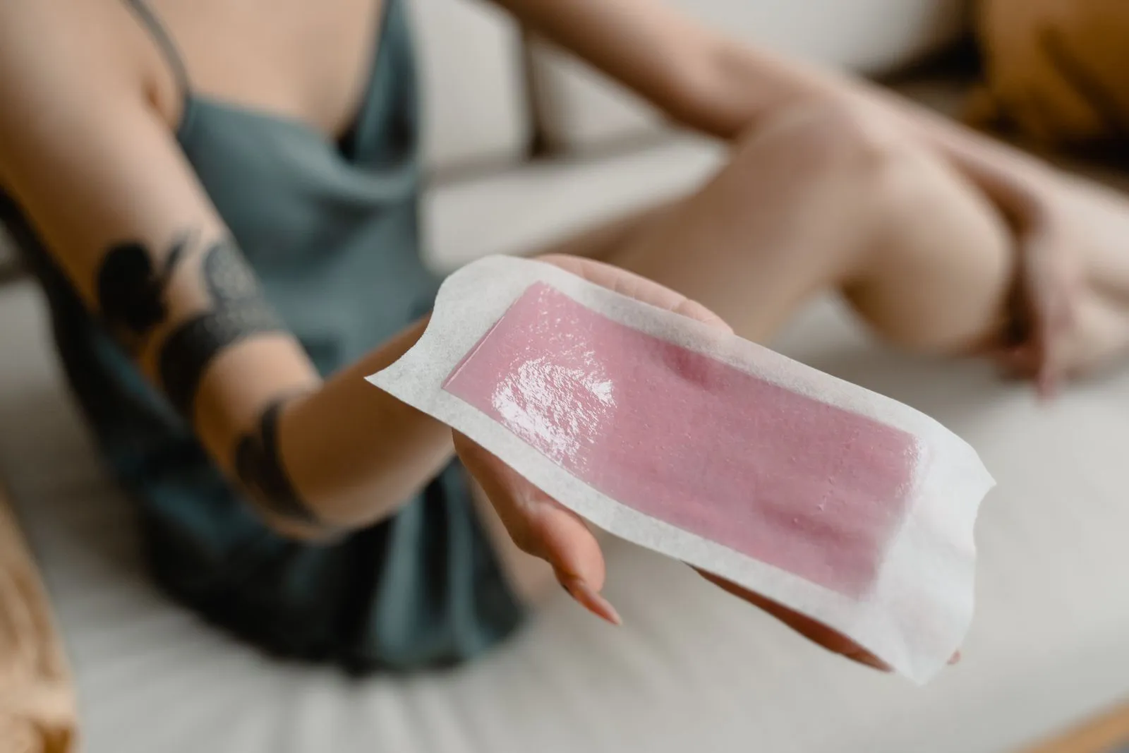 Close-up of a woman's hand holding a hair removal wax strip