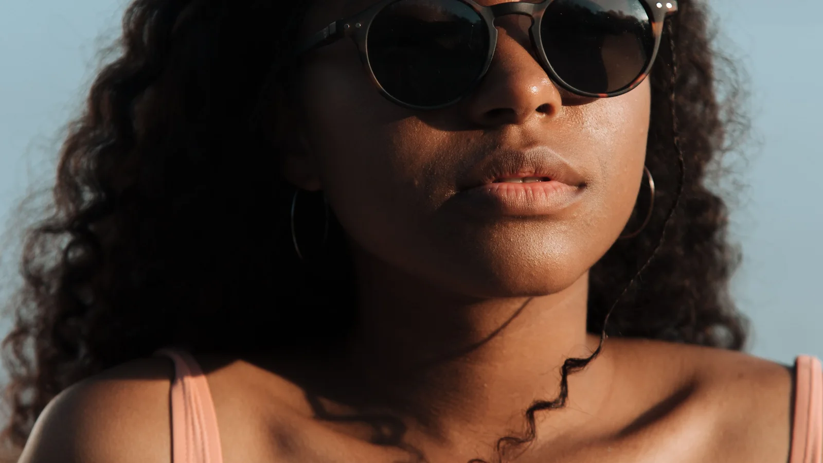 Close-up portrait of a woman wearing sunglasses outdoors.