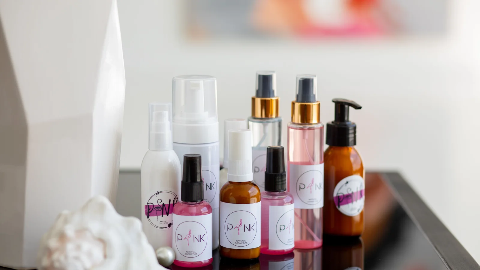 A collection of cosmetic pump bottles, jars and tubes on a pale surface.