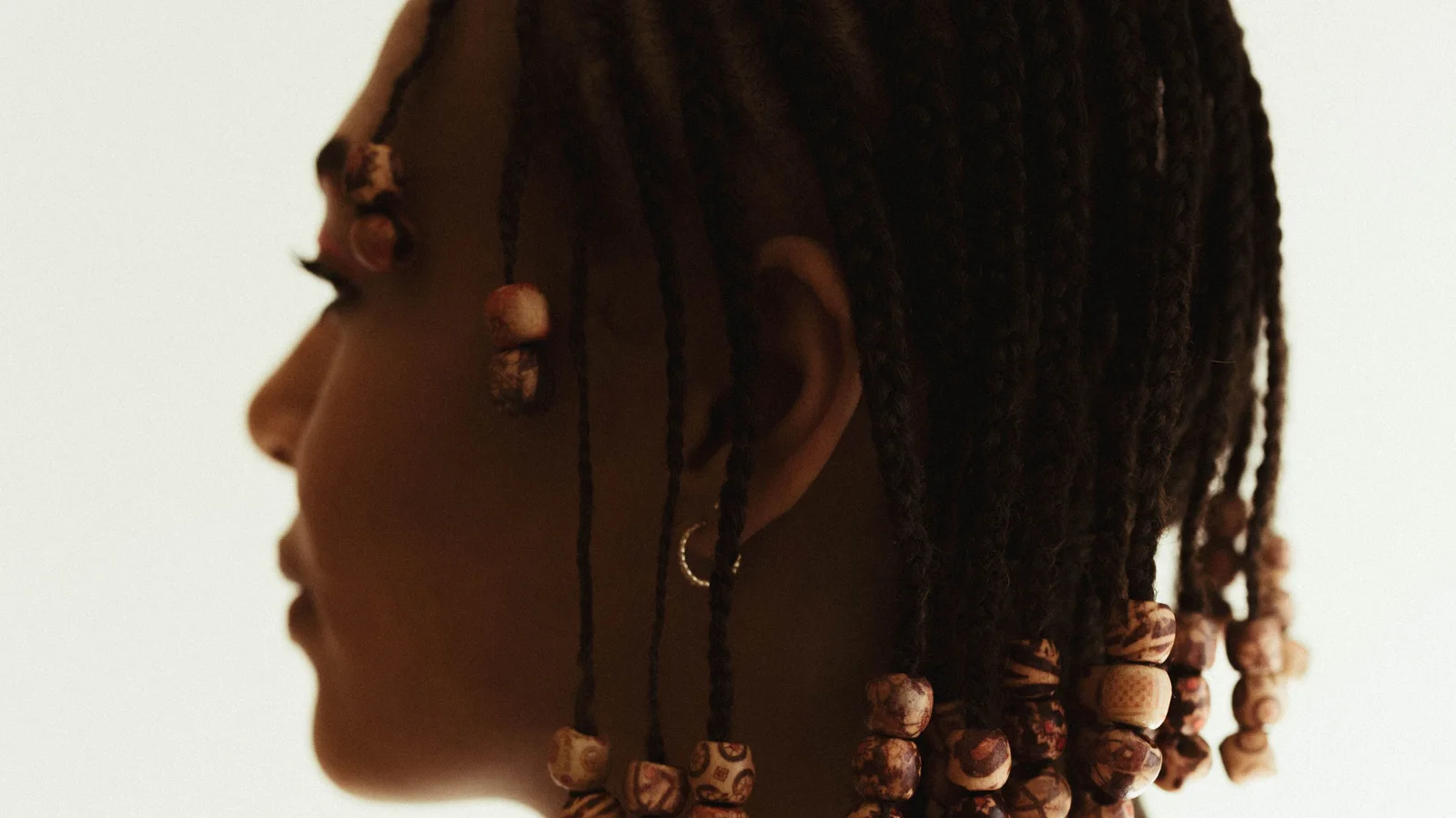 Side profile of a woman with short braids and bead details.