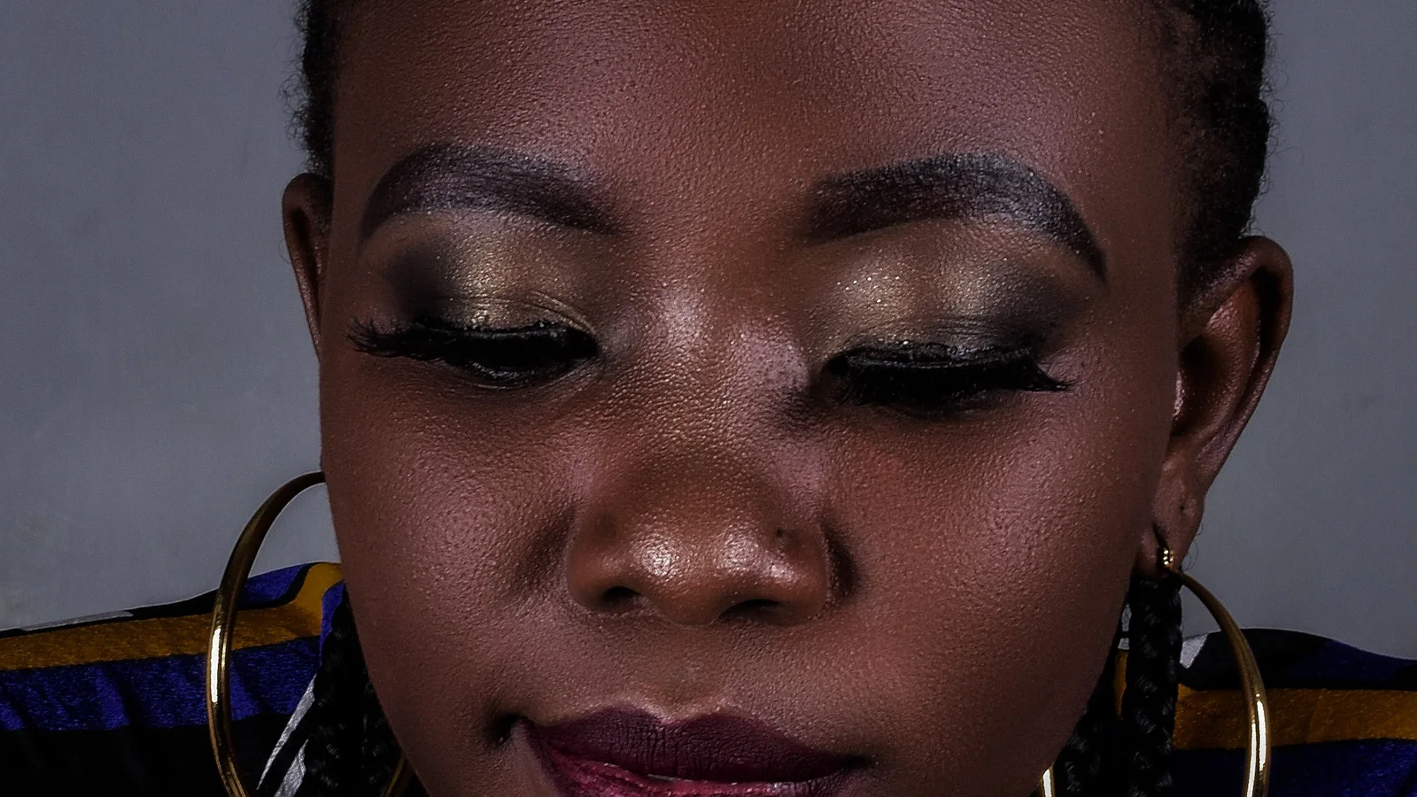 A woman with braided hair looking down with softly blended eye make-up.