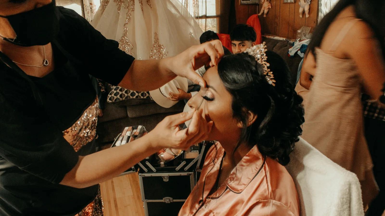 A make-up artist working around a seated woman's face during preparations.