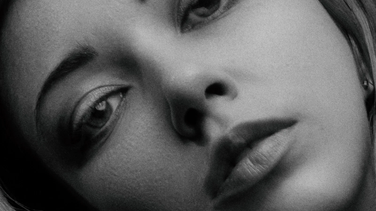 Black-and-white close-up portrait of a woman against a plain background.