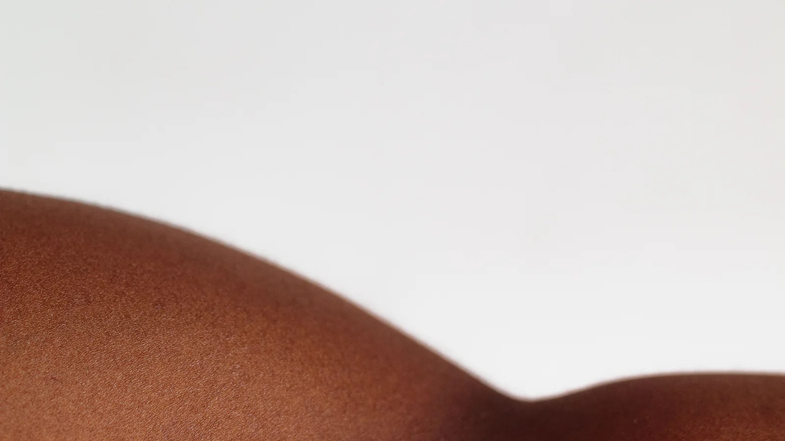 Close-up of brown shoulder skin against a pale background.