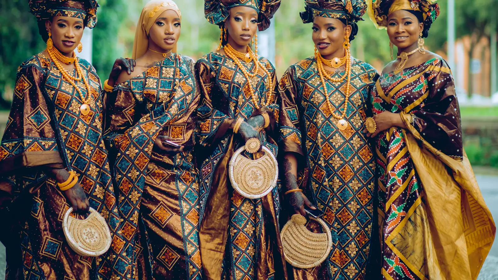 A group of women wearing patterned dresses and headwraps outdoors.