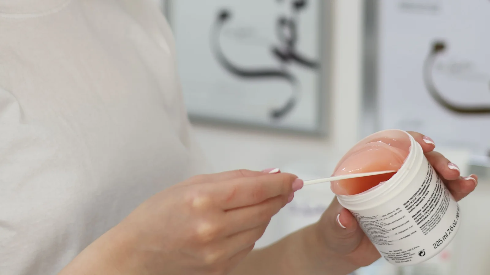 A woman looking down at a cosmetic container in her hands.