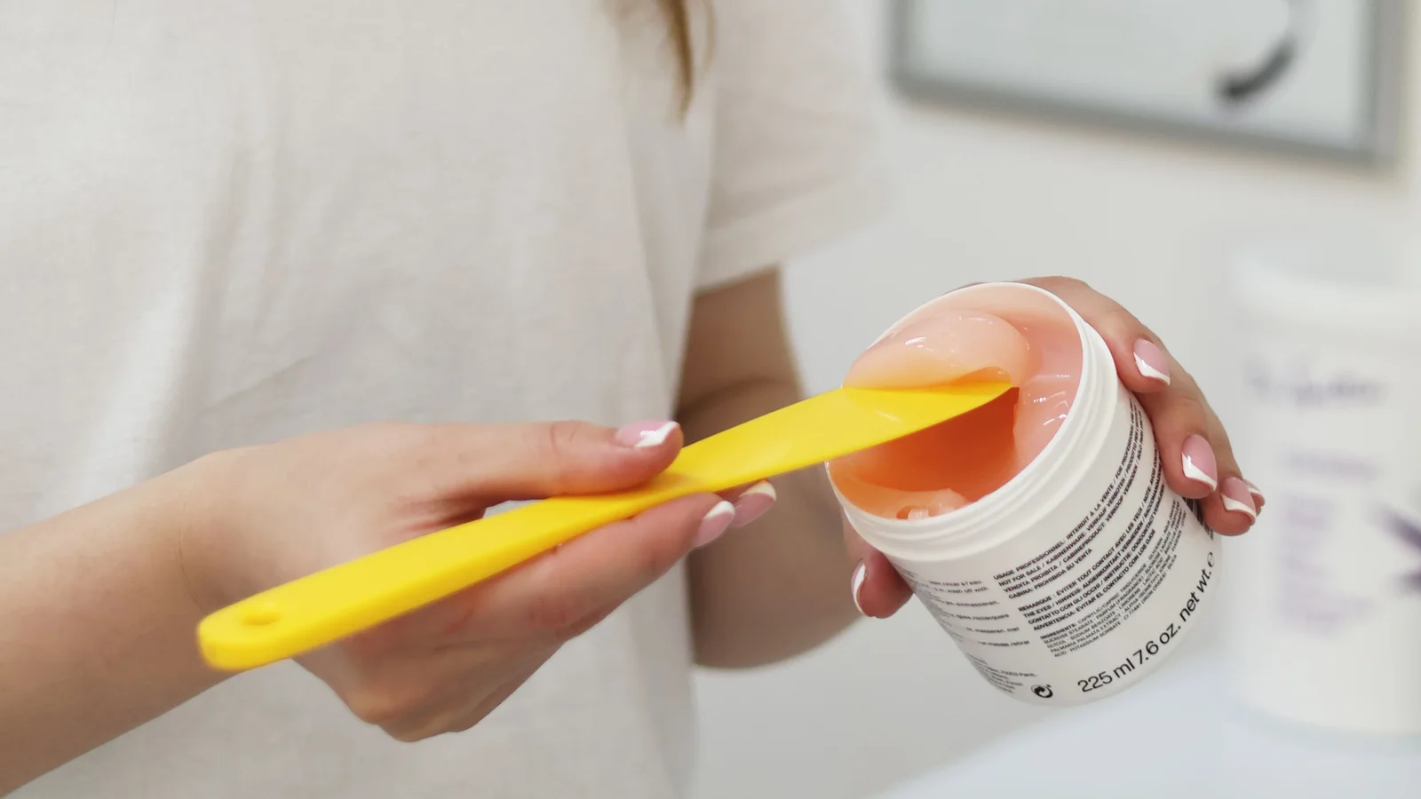 A woman lifting product from an open container with a small spatula.