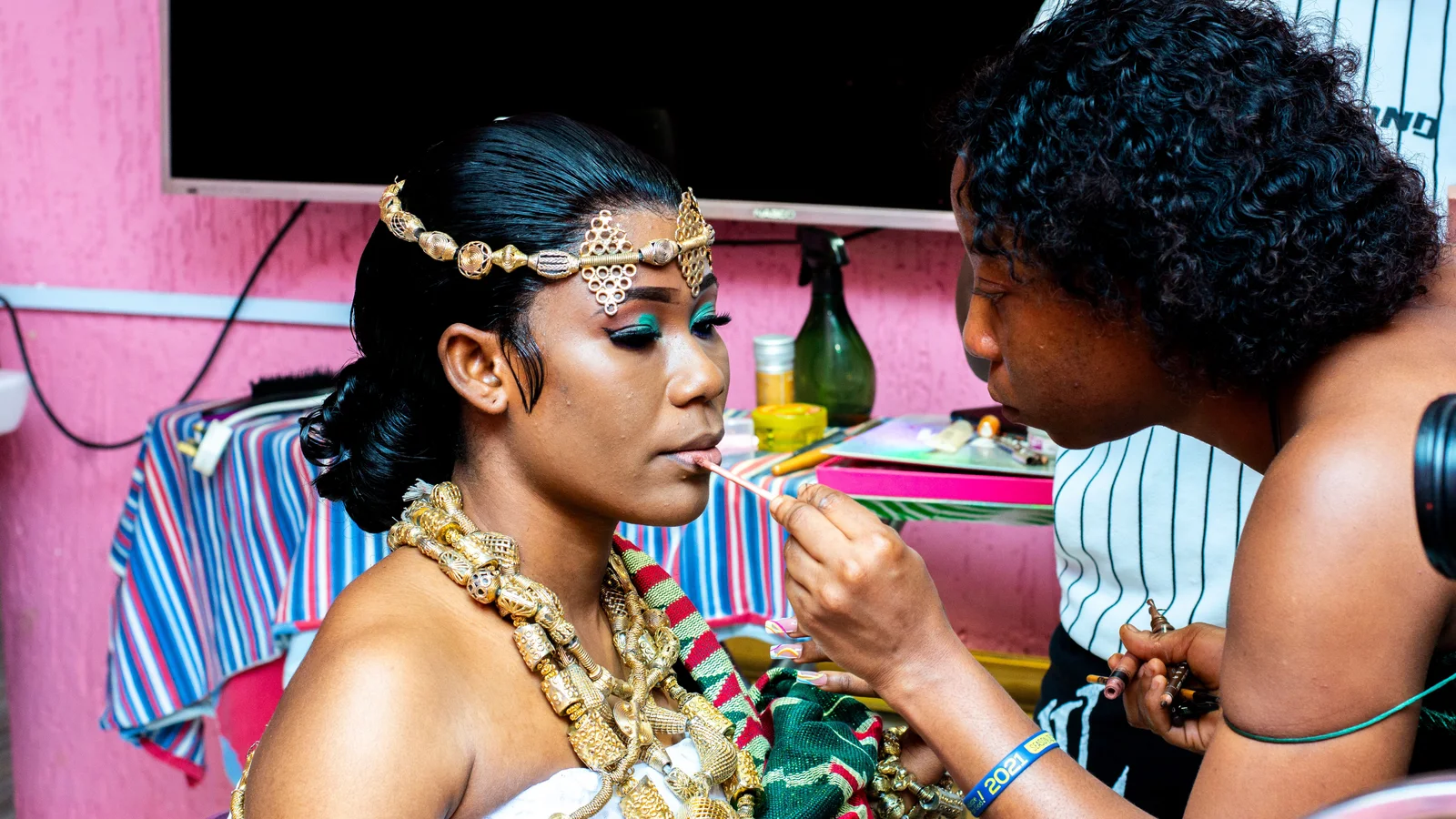 A woman wearing ornate jewellery and headwear while having make-up applied.