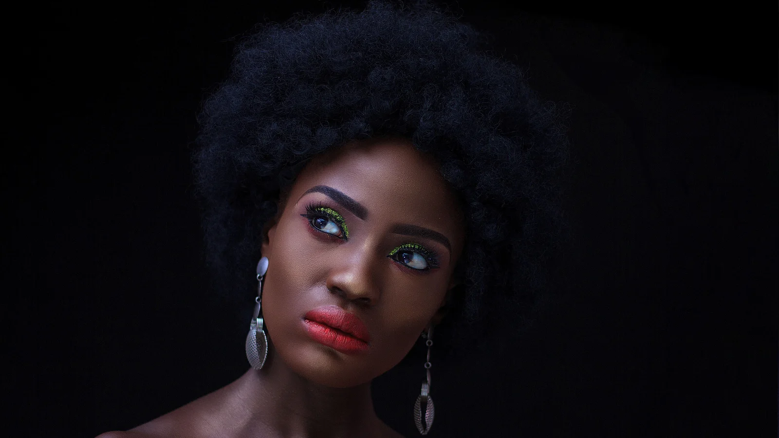 Portrait of a woman with an afro, defined eye make-up and red lipstick.