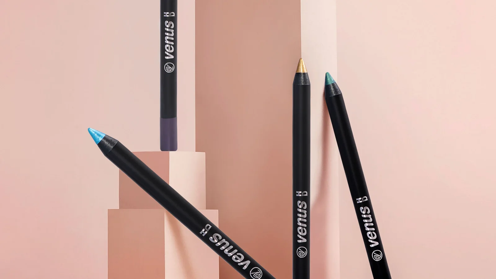 Several coloured cosmetic pencils arranged against a pink background.