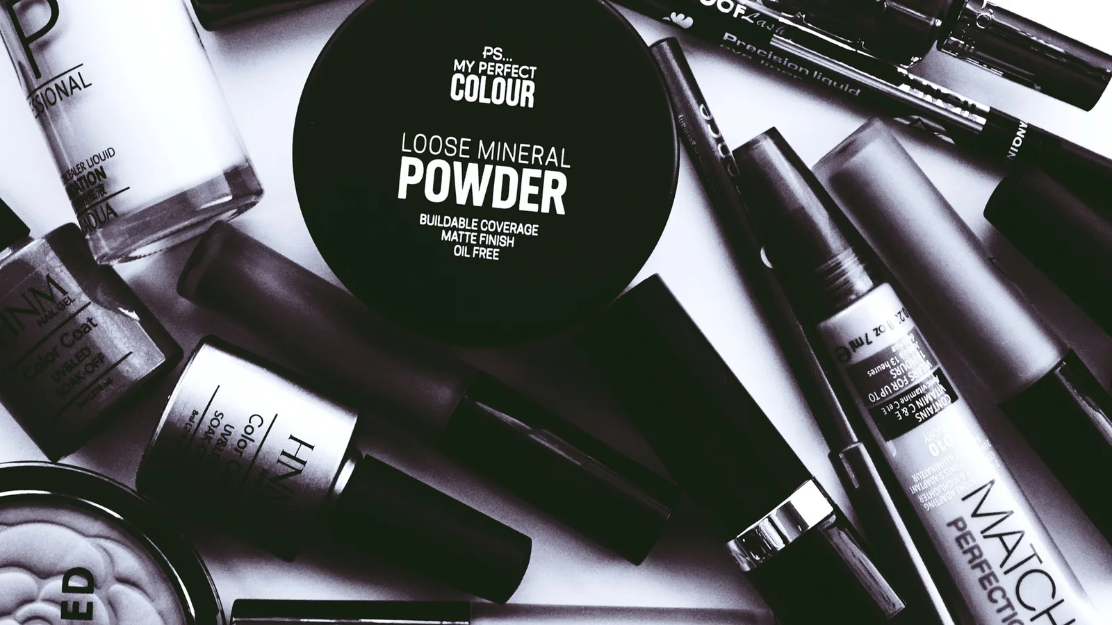 A powder container, spray bottles and other cosmetics arranged on a pale surface.