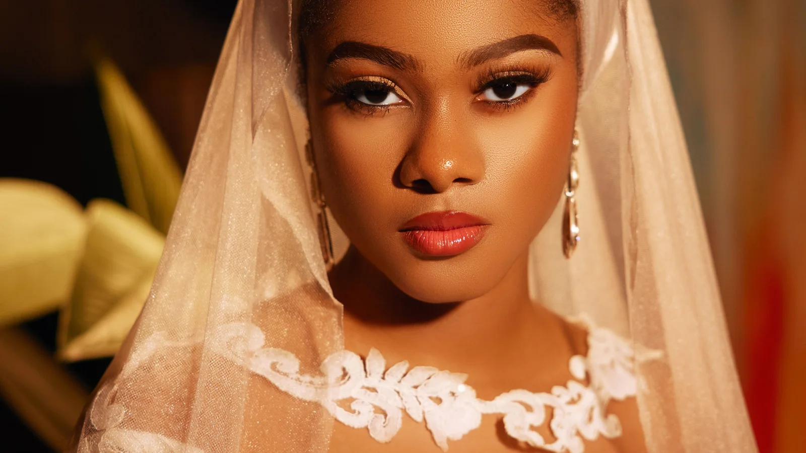 Portrait of a woman wearing a white lace dress and veil.