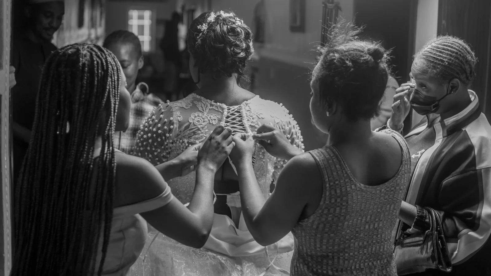 Black-and-white photograph of women helping during bridal preparations.