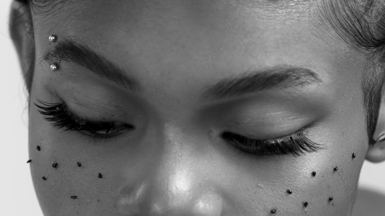 Black-and-white portrait of a woman with small decorative marks across her cheeks.
