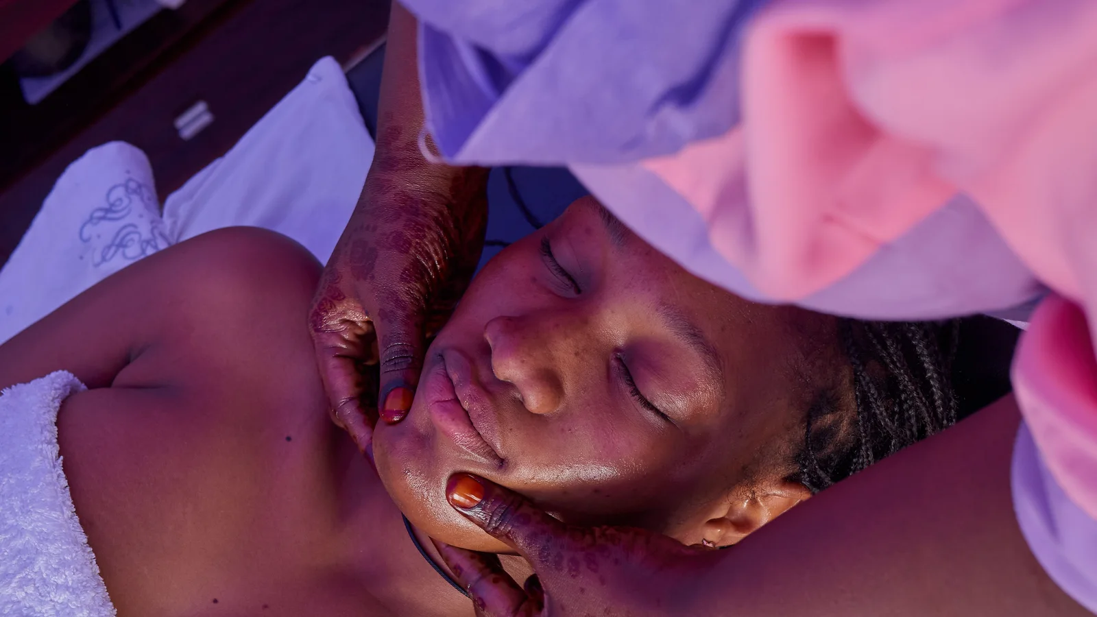 Hands supporting a woman's face during a facial massage.