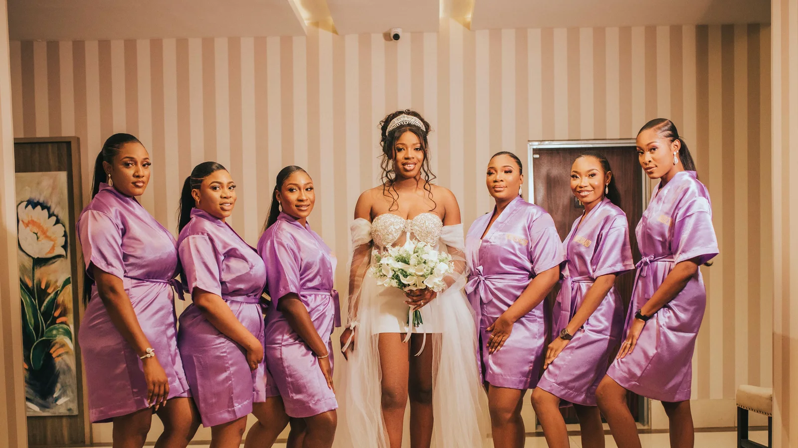 A woman in white standing with women wearing lavender robes.